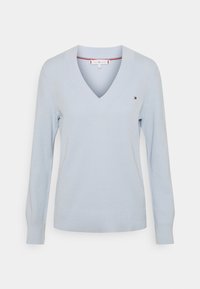 Jasnoniebieski dziany sweter z dekoltem w serek, długimi rękawami i delikatną prążkowaną fakturą. Posiada małe logo na piersi oraz gładki dół.