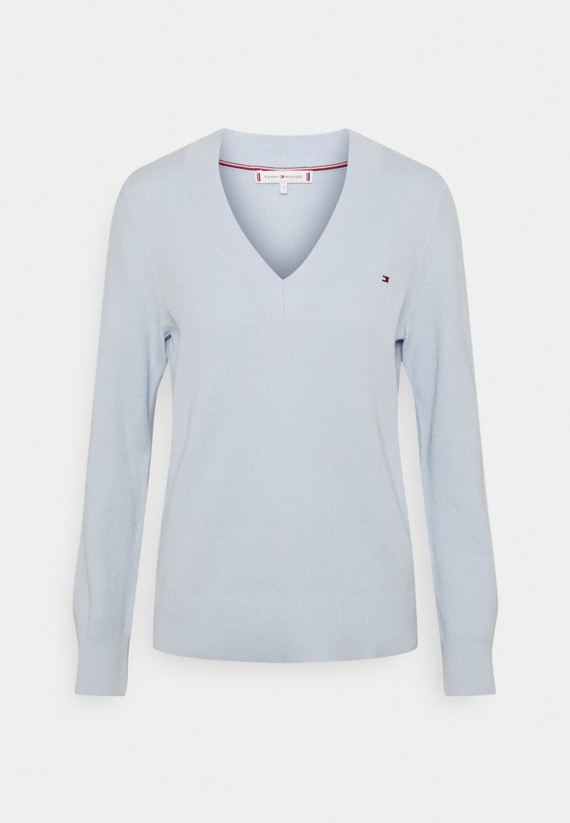 Jasnoniebieski dziany sweter z dekoltem w serek, długimi rękawami i delikatną prążkowaną fakturą. Posiada małe logo na piersi oraz gładki dół.