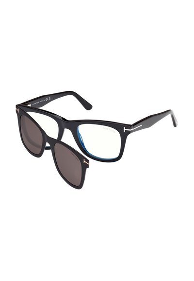 Zwarte rechthoekige Tom Ford-bril met afneembare, donkergetinte clip-on zonnebrillenlens gedeeltelijk bevestigd aan het montuur.