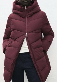 Chaqueta acolchada burdeos con capucha, que presenta un cierre frontal con cremallera, diseño de acolchado horizontal y bolsillos laterales. Textura suave y longitud hasta medio muslo.
