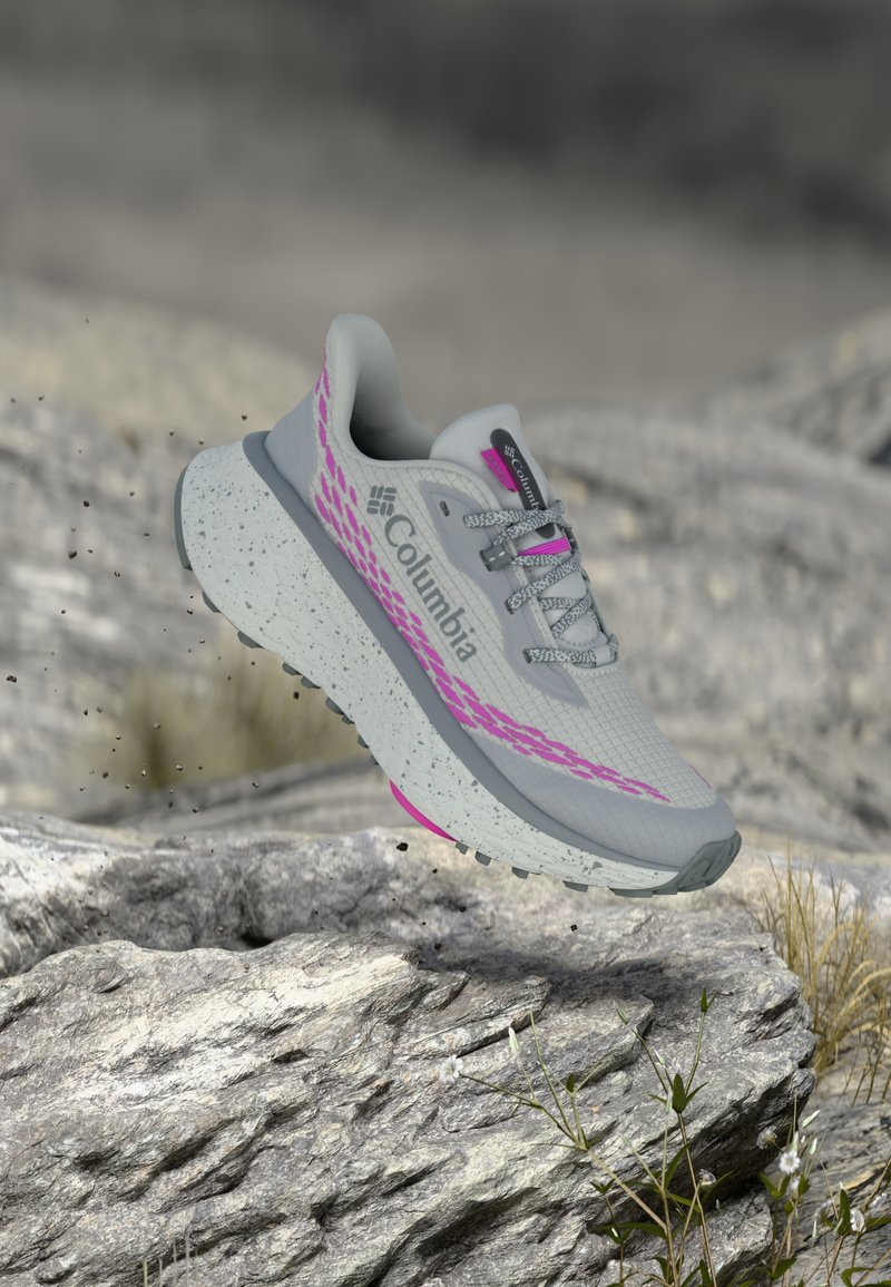 Αθλητικό παπούτσι σε ανοιχτό γκρι με ροζ λεπτομέρειες. Διαθέτει υφασμάτινο επάνω μέρος με υφή, αντανακλαστικά στοιχεία και μεσαία σόλα με κηλίδες. Η εξωτερική σόλα παρουσιάζει σχέδιο για πρόσφυση.