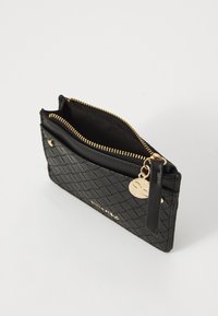 Portefeuille en cuir noir avec une texture matelassée, fermeture éclair dorée et quincaillerie. Il dispose d'une poche extérieure et d'une boucle pour porte-clés.