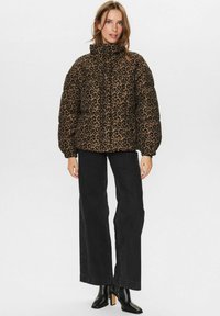 Puhasta jakna v leopardjem vzorcu, ki ima visok ovratnik, prešito zasnovo in elastične manšete. Nosi jo z širokimi črnimi kavbojkami in gležnjarji.