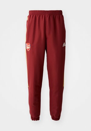 Pantaloni sportivi bordeaux con strisce laterali gialle, vita elastica e polsini elastici. Presenta un logo dell'Arsenal sulla coscia sinistra.