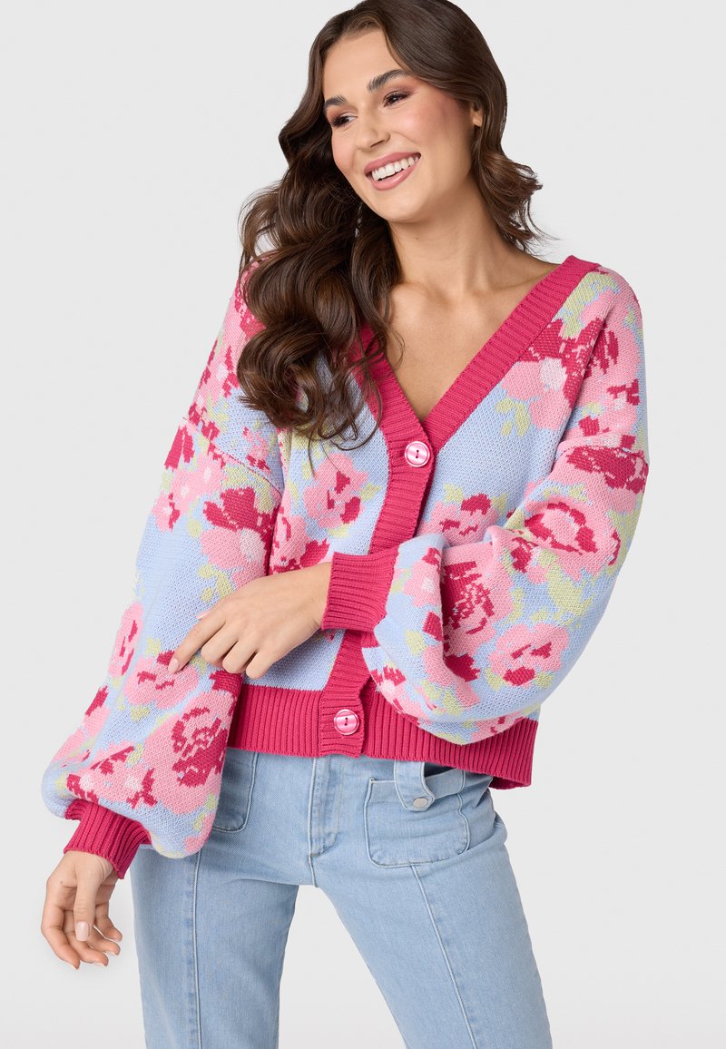 Färgglad blommig kofta i blått och rosa, med V-ringning, puffärmar, ribbade ärmslut och rosa knappar för stängning.
