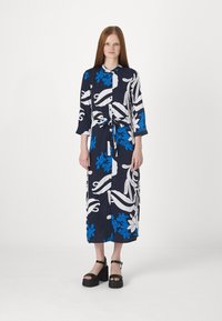Vestido longo com padrão floral azul e branco, com cintura pronta, destacando um colarinho e mangas de três quartos, em um tecido fluido.