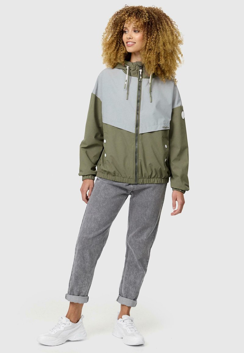Kleurgeblokte windbreaker jas met een lichtgrijze bovenkant en een olijfgroene onderkant. Voorzien van een ritssluiting aan de voorkant, een verstelbare capuchon en elastische manchetten.
