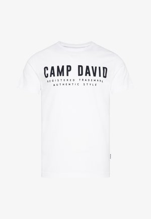 T-shirt in cotone bianco con testo stampato nero: "CAMP DAVID," e slogan "MARCHIO REGISTRATO STILE AUTENTICO." Design classico con scollo tondo.