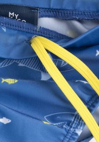 Simbyxor med ett blått tyg som har mönster av vita och gula fiskar, en gul dragsko och en mjuk, vadderad textur.