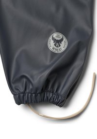 Marineblå vandtæt stof med rynket elastisk kant, med et cirkulært gråt logo med en elg og "WHEAT" tekst. Snoretræk detalje synlig.