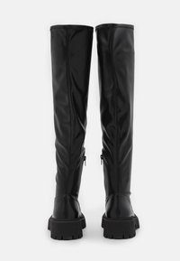 Svarta knähöga stövlar gjorda av slät syntetiskt material, med en strukturerad design, texturerad sula och sidodragkedjor.