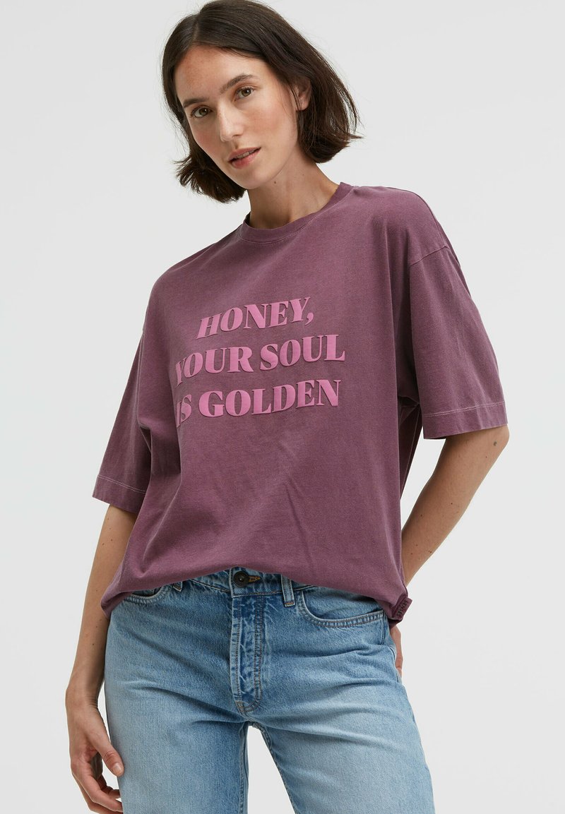 Purple cotton t-shirt with short sleeves, featuring bold text in light pink: "HONEY, YOUR SOUL IS GOLDEN." Casual, relaxed fit.