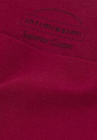 Burgundowa bawełniana tkanina o żebrowanej fakturze, z metką oznaczającą "intimissimi Superior Cotton."