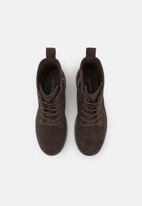 Stivaletti in suede marrone alla caviglia con chiusura a lacci e cerniera. Texture liscia, punta rotonda e linguetta rinforzata sul tallone per una facile calzata.