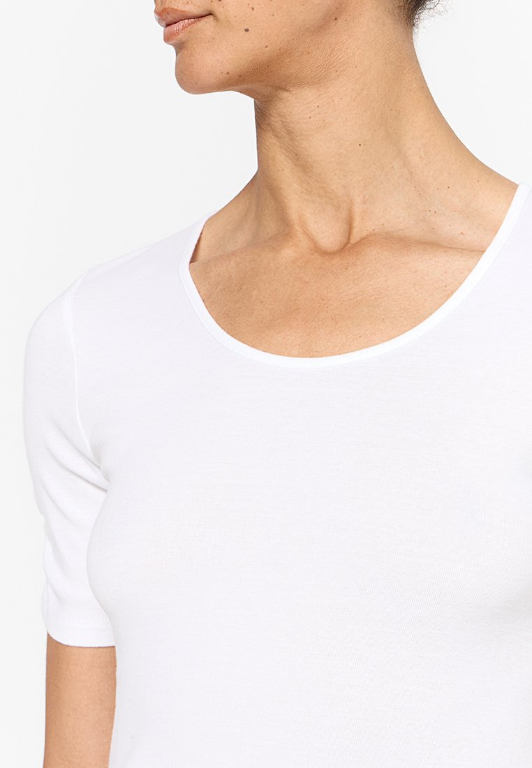 Top blanco de algodón de manga corta con un escote amplio y textura suave, que presenta un corte recto y detalles de costura mínimos.