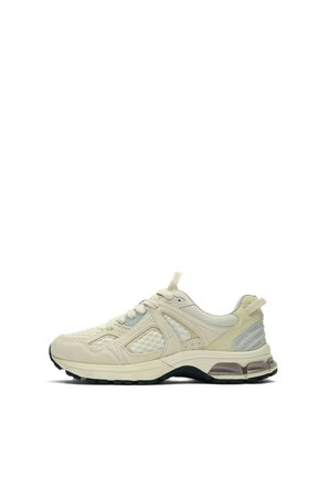 Lahek bež športni čevelj z mrežastimi paneli, z zavezovanjem, blaženo podplato in črnim grobo profiliranim podplatom, prikazan v stranski profil.