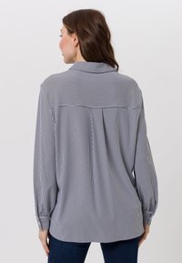 Schwarz-weiß gestreiftes Langarmshirt mit Kragen, ausgestattet mit einem Rückenpasse und Falten, gefertigt aus leichtem Stoff.