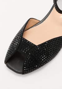 Must musta peep-toe kingad tekstureeritud ülemise osaga, millel on väikesed ruudud, siledast nahast sisetald ja avatud disain, mis toob esile varbad.