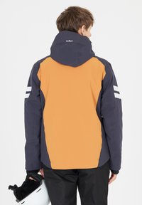 Skijakke med et tofarvet design med orange og navy paneler, en hætte og reflekterende hvide striber på ærmerne.