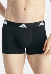 Boxer shorts en coton noir avec une large taille élastique ornée d'un logo à trois bandes blanches. Design ajusté avec une texture lisse.