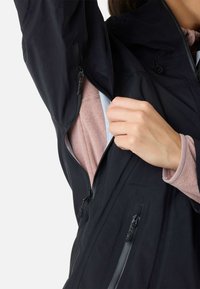 Sort vandtæt jakke med lynlåse, der viser en lys rosa indvendig fleece. Har justerbar hætte og struktureret stof.