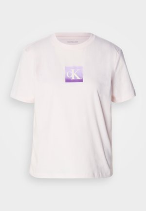 Svijetložuta pamučna majica s kratkim rukavima, s kvadratnim ljubičastim grafičkim logotipom sa bijelim slovima "cK" u središtu.