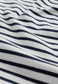 Baumwollstoff mit weißen und marineblauen horizontalen Streifen, glatte Textur und leicht zerknittertes Aussehen, das einen deutlichen Farbk starkkontrast zeigt.