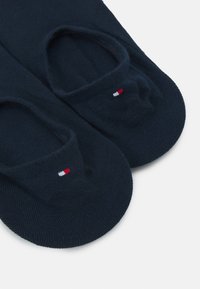 Námořnické modré ponožky do kotníků vyrobené z měkké tkaniny, s malým tříbarevným logem (červená, bílá, modrá) na horní straně.