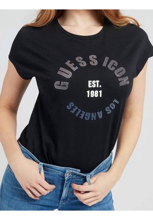 Schwarzes T-Shirt mit kurzen Ärmeln und Rhinestone-Grafik, auf der "GUESS ICON EST. 1981" und "LOS ANGELES" in Blau und Weiß steht. Weicher Stoff, lockere Passform.