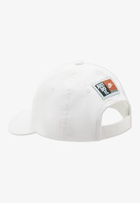 Λευκό καπέλο με καμπυλωτή γείσο, που διαθέτει πολύχρωμο ορθογώνιο κομμάτι με την επιγραφή "JUST DO IT" και ένα λογότυπο. Ρυθμιζόμενο πίσω λουράκι.