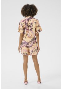 Korte mouwen, button-up shirt en bijpassende shorts in een multikleurig abstract patroon; lichte stof; pasteltinten van geel, roze en paars.