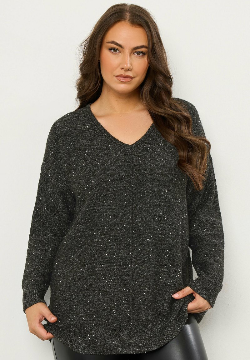 Schwarzer Pullover mit V-Ausschnitt, langen Ärmeln und lockerer Passform; texturiert mit silbernen Sprenkeln überall. Saum geschwungen am unteren Ende.