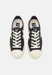 Sneakers neri in tela con lacci color crema e punte in gomma. Presentano un logo sulla linguetta e strisce laterali a contrasto.