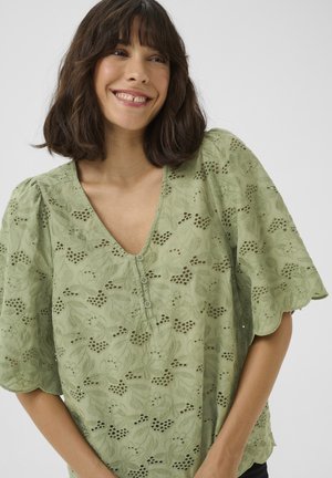Grüne Bluse mit V-Ausschnitt, puffierten kurzen Ärmeln, floralem Stickerei und Knopfverschluss mit Ausschnittmustern. Texturiertes, leichtes Material.