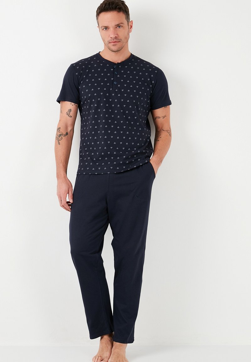 Conjunto de pijama azul marino con parte superior de manga corta que presenta un sutil patrón geométrico y pantalones de un color sólido. Tejido suave y liviano.