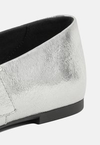 Scarpa piatta argento con una parte superiore in sintetico testurizzato, punta arrotondata e suola in gomma nera. Presenta cuciture sottili e un rivestimento interno liscio.