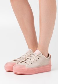 Ljusbeige canvas sneakers med en strukturerad rosa gummisula och detaljer. Rund tå med snörning och subtila sidostygn detaljer.