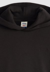 Sudadera negra de tejido suave con un ajuste relajado. Cuenta con un bolsillo canguro, capucha ajustable y un logo de Levi's bordado en el pecho.