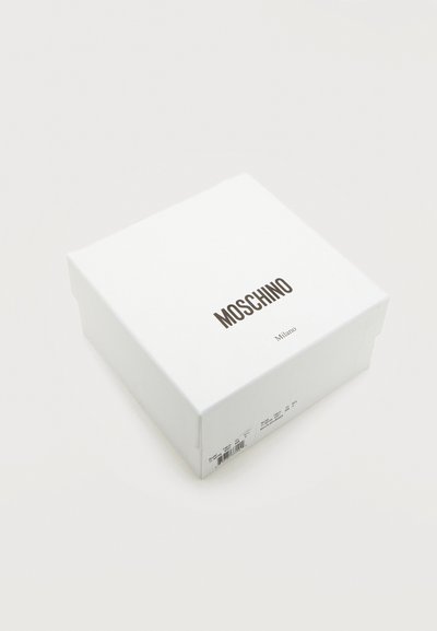 Λευκό τετράγωνο κουτί με το λογότυπο "MOSCHINO" και την ένδειξη "Milano" τυπωμένη από κάτω, τοποθετημένο σε απλό λευκό φόντο.