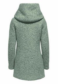Manteau texturé vert clair à manches longues avec un grand col haut, présenté de dos sur un fond neutre.