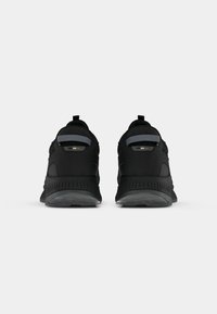 Baskets de sport noires avec une finition texturée, dotées d'un col rembourré, d'une languette à l'arrière et d'accents gris au niveau du talon. Semelle en caoutchouc pour une meilleure adhérence.