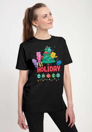 Sort t-shirt med farverige tegneserieedderkopper, der dekorerer et juletræ. Teksten siger "Juleglæde" med festlige dekorationer og mønstre.