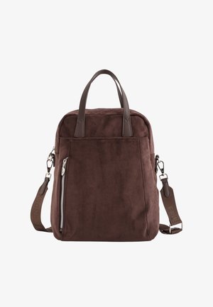 Sac à dos en daim marron avec double poignée supérieure, bandoulière réglable, poche zippée à l'avant et détail de marque discret sur la sangle.