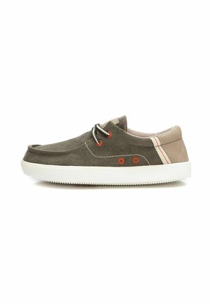 Zapatillas de lona en verde oliva, con suelas de goma blanca, ojales naranjas y detalles en crema en el talón. Punta redonda con diseño de cordones.
