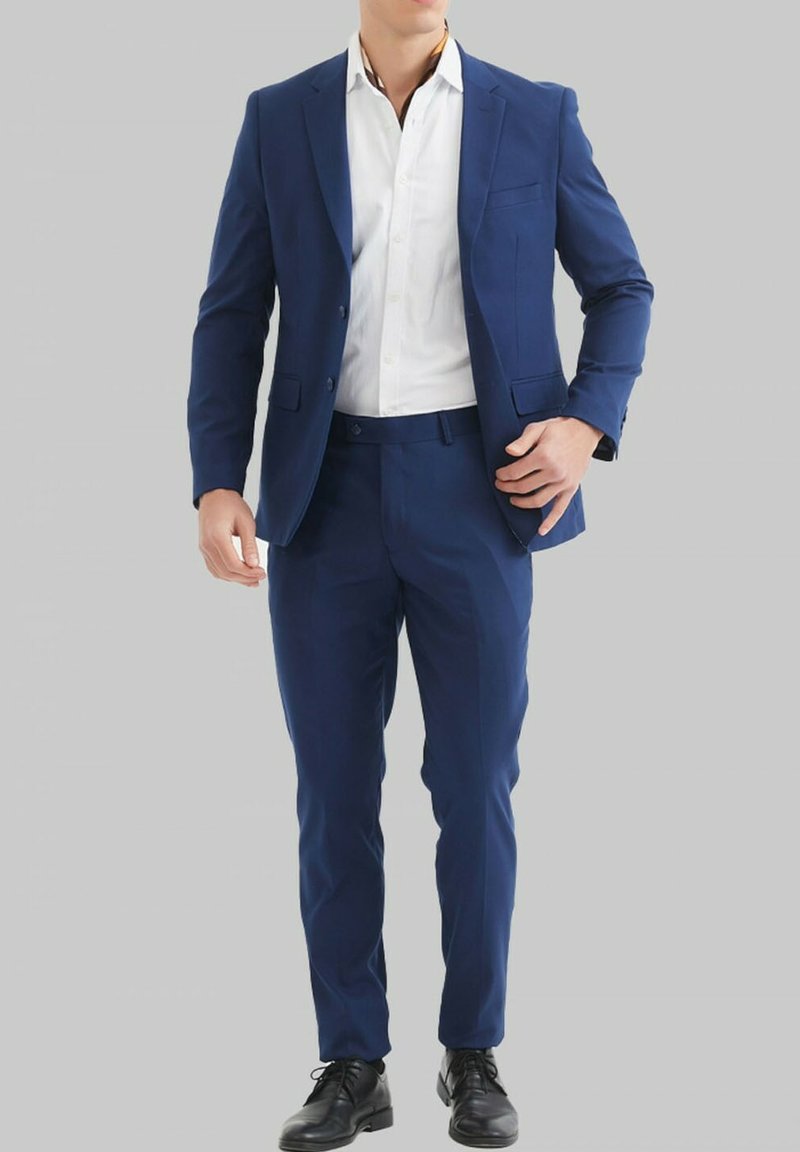 Costume bleu marine à coupe slim, doté d'un blazer à bouton unique et de pantalons à jambe plate. Assorti avec une chemise blanche et des chaussures noires.