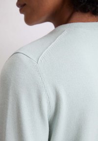 Maglione a maglia di colore azzurro chiaro con scollo rotondo e maniche a raglan, caratterizzato da una consistenza morbida e dettagli di cucitura discreti sulle spalle.