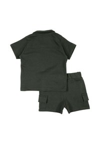 T-shirt à manches courtes en coton vert foncé et shorts assortis avec deux poches latérales, présentant une coupe décontractée et une texture douce.