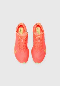 Nike running shoes featuring a bright coral mesh upper, thin laces, and a neon green outsole. Includes logo detail on the side.