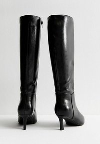 Czarne skórzane kozaki sięgające do kolan o gładkim wykończeniu, zwężającym się kształcie i 5-centymetrowych obcasach; zamek z tyłu ułatwiający zakładanie.