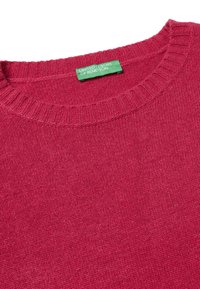 Fuchsia gestrickter Pullover mit geripptem Ausschnitt, ausgestattet mit einem grünen Markenlabel. Weiche Textur und einfarbig ohne Muster oder Verzierungen.